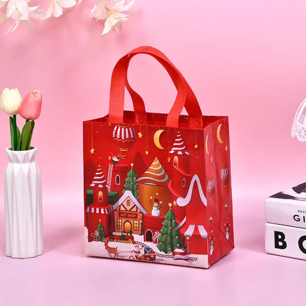 A red non-woven gift tote bag with festive Christmas prints and a handle, set against a pink background.