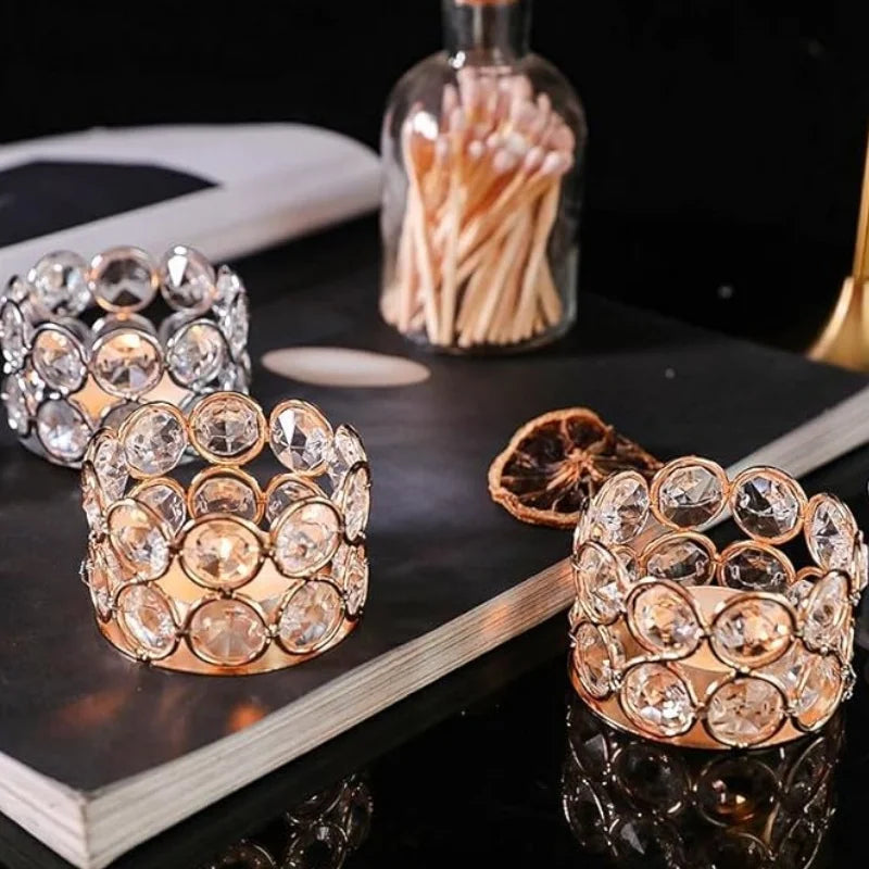 A set of crystal tealight candle holders with metal bases displayed on a dark surface.