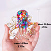 A hand holds a sparkling crystal octopus statue with colorful beads and gold accents.