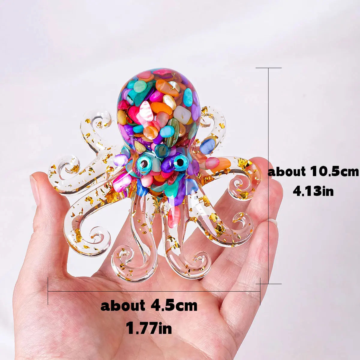 A hand holds a sparkling crystal octopus statue with colorful beads and gold accents.