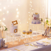 Elegant transparent acrylic cake display rack with a tiered white cake decorated for a celebration.