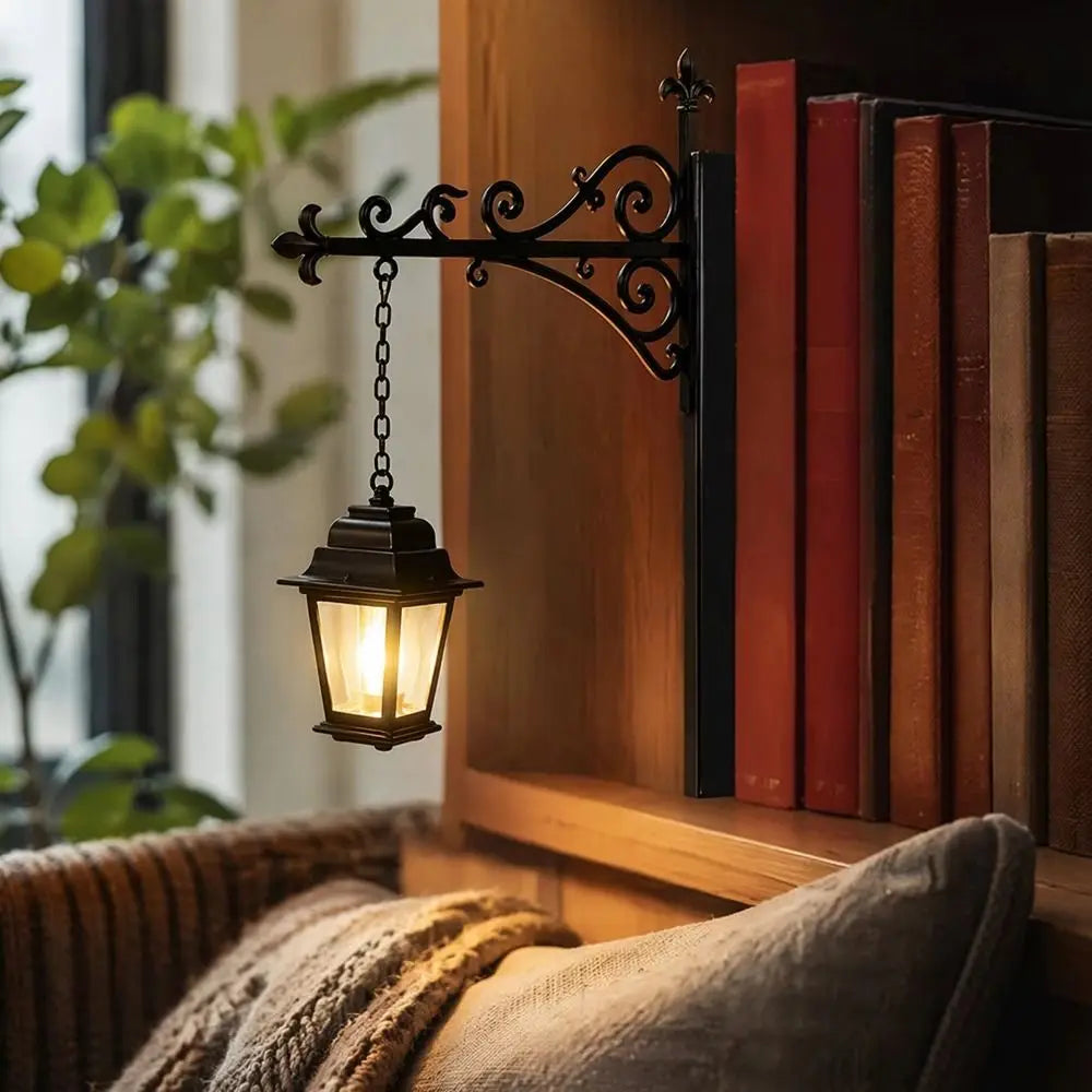 A vintage black wrought iron lantern lamp hangs on a wooden shelf next to a row of old books.