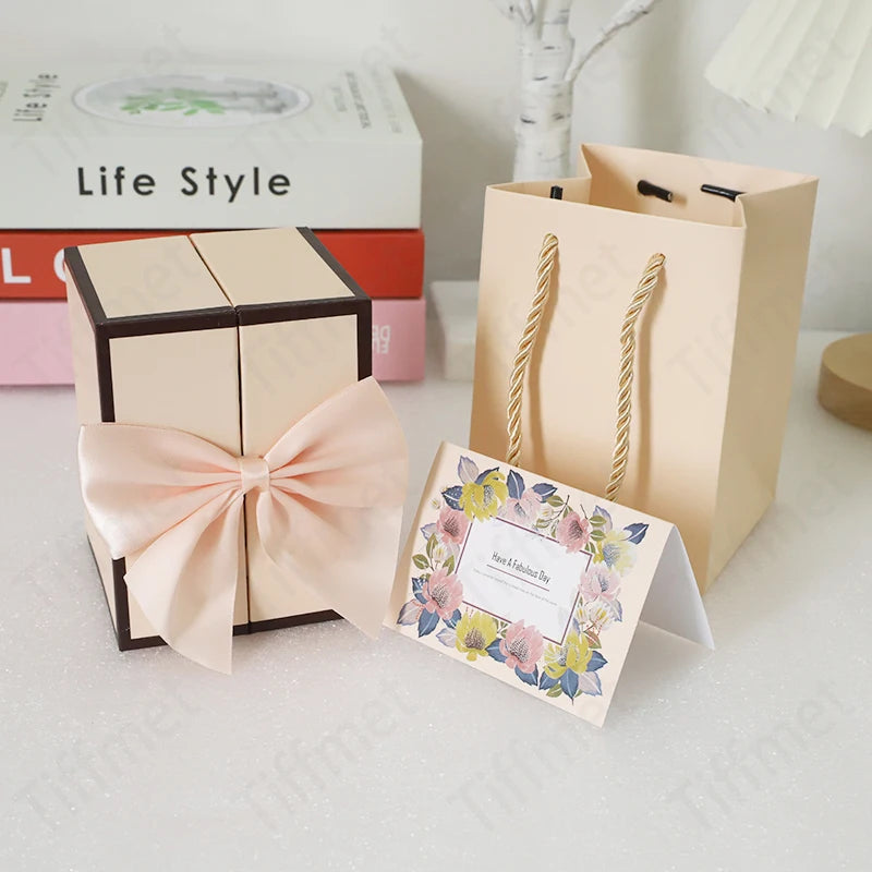 A light pink rose pendant necklace is displayed next to a natural kraft paper gift box and stacked books.
