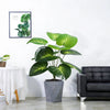 A large artificial palm tree with vibrant green leaves in a gray planter on a modern living room shelf.