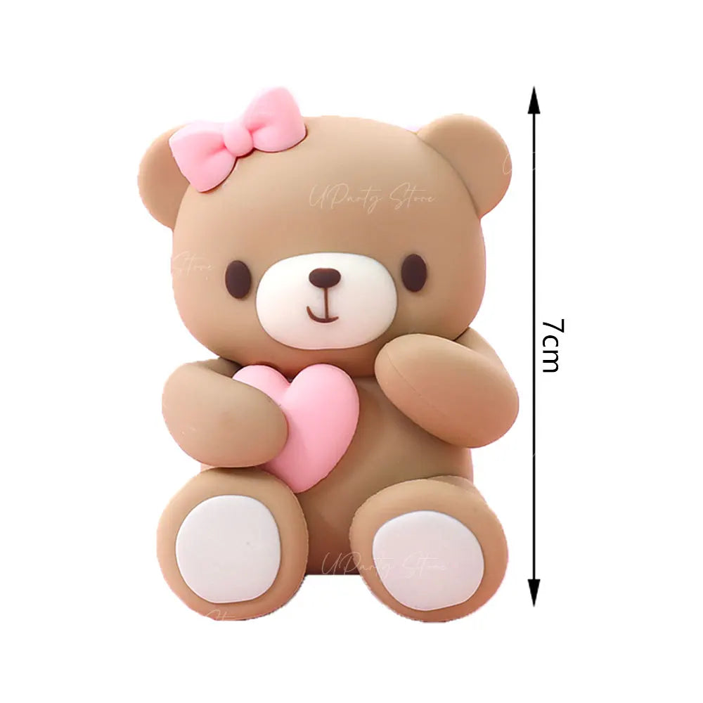 A cute brown teddy bear figurine with pink accents and a bow, shown against a white background.