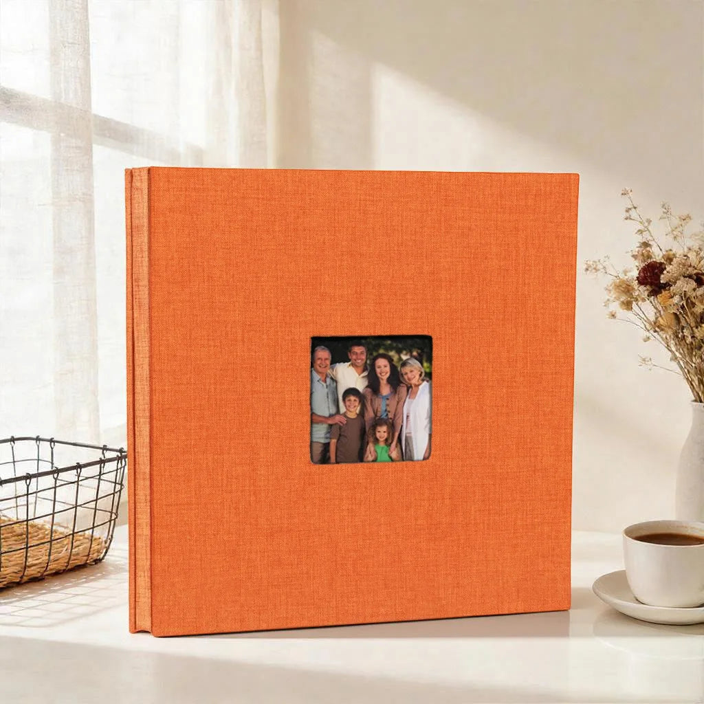 An orange linen front scrapbook memory book with a small photo insert, resting on a white surface.