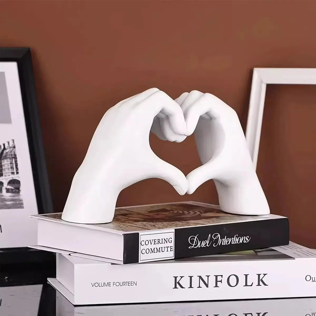 White resin hand sculpture shaped like a heart, resting on a stack of books.