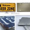 A yellow metal license plate with the text Welcome Beer Zone and a silver metal plate.