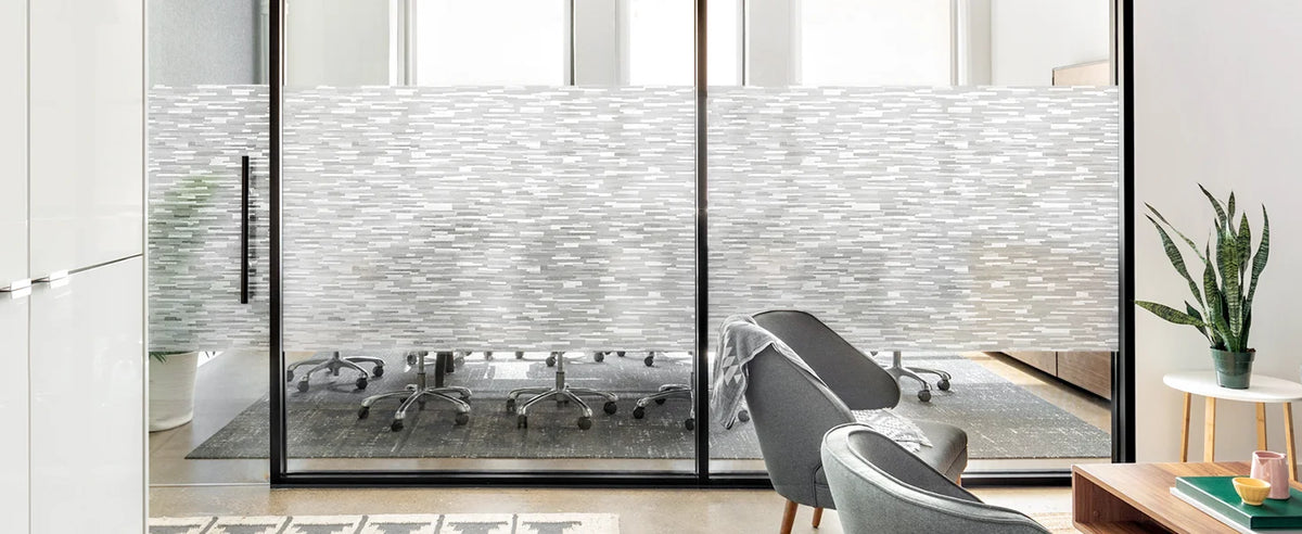 A frosted glass window privacy film is installed in a modern interior, obscuring a view of a table and chairs.