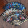 An elegant plum blossom folding fan with intricate floral patterns in blue, green, and red tones.
