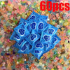 A pile of sixty pieces of blue mystery bags scattered on a bed of colorful glow in the dark resin decor.