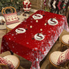 A red Christmas poinsettia rectangle tablecloth set for a dining table with festive holiday decor.
