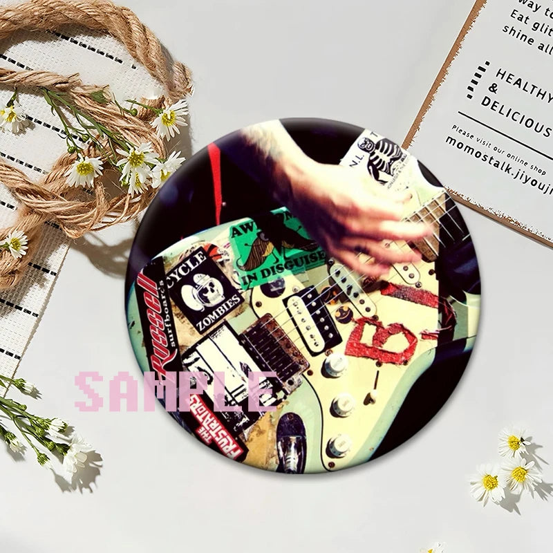 A close-up photo of a black button pin featuring punk band album art and text on a light green background.