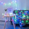 A photo frame sits on a table surrounded by glowing LED star fairy lights draped over a blue couch.