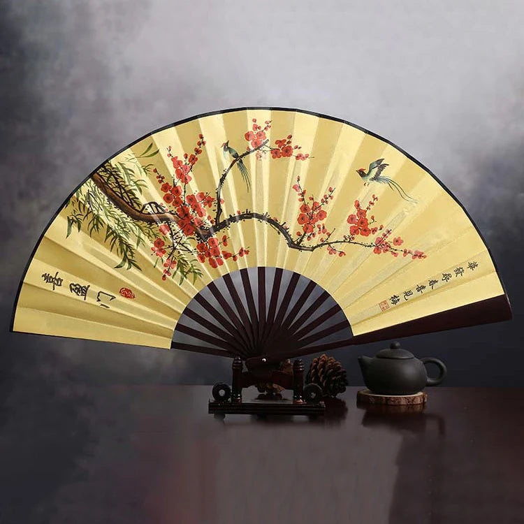 A retro folding silk and bamboo decorative fan with a light yellow background featuring red blossoms and birds.