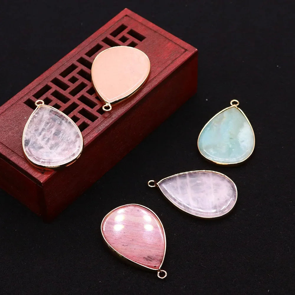 A collection of pink and green agate pendants displayed on a wooden box.