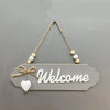 Rustic wooden welcome sign with the word Welcome carved into the wood and tied with twine.
