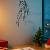 A black line art silhouette of a girl with hair covering her face on a white wall next to a notebook and wrapped gifts.
