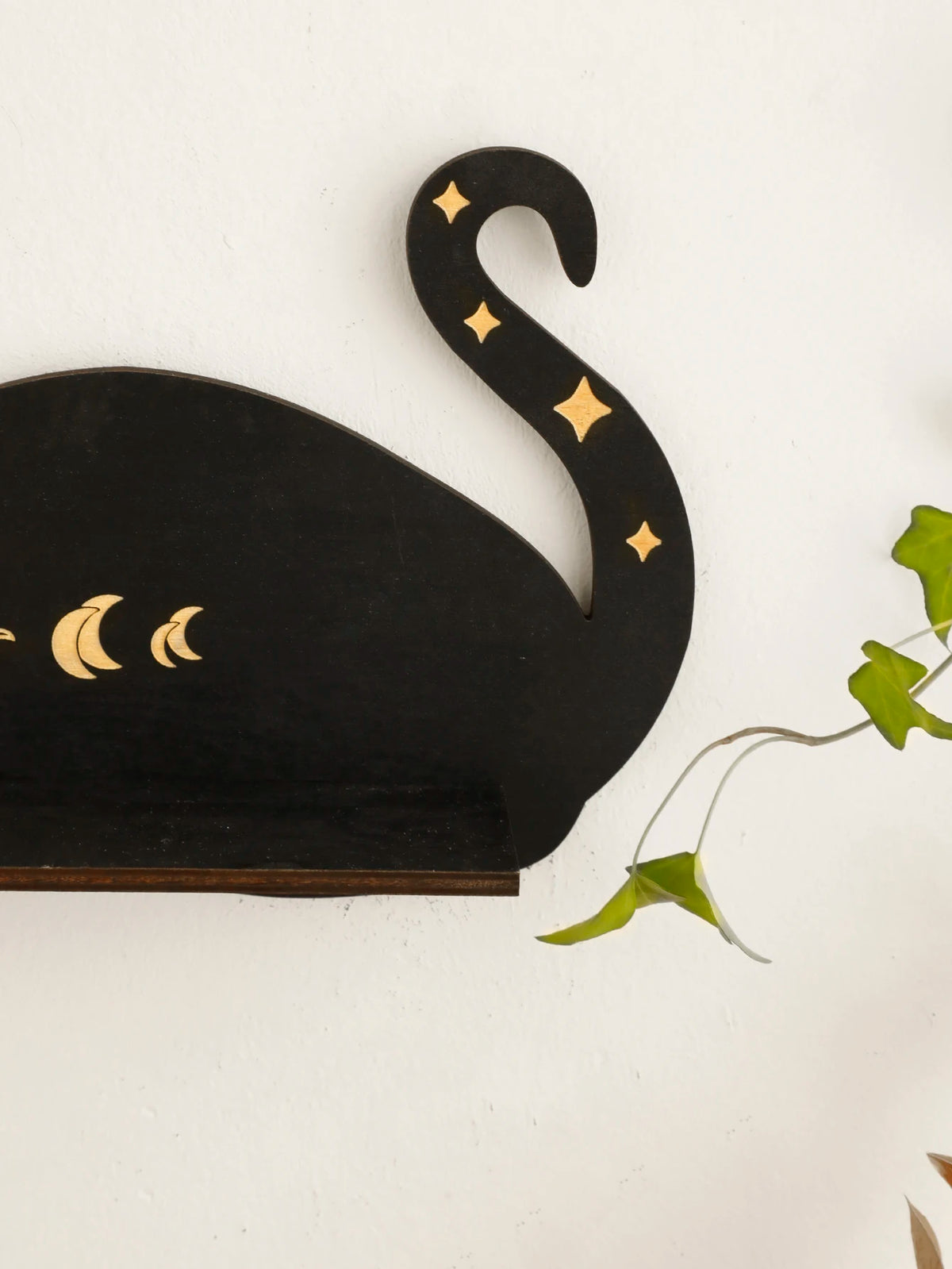 A black wall shelf featuring a silhouette of a cat with crescent moon accents.