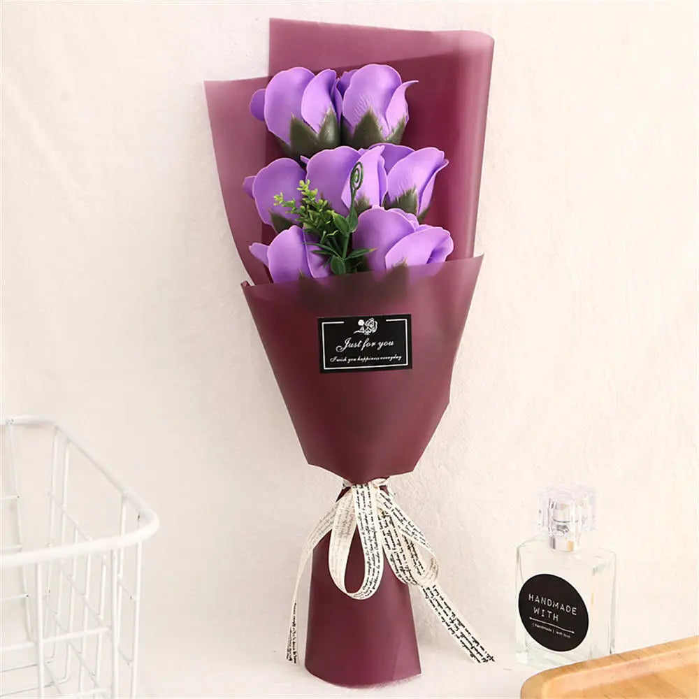 A purple rose bouquet in a dark pink paper holder with a gold tag and twine tied around the base.