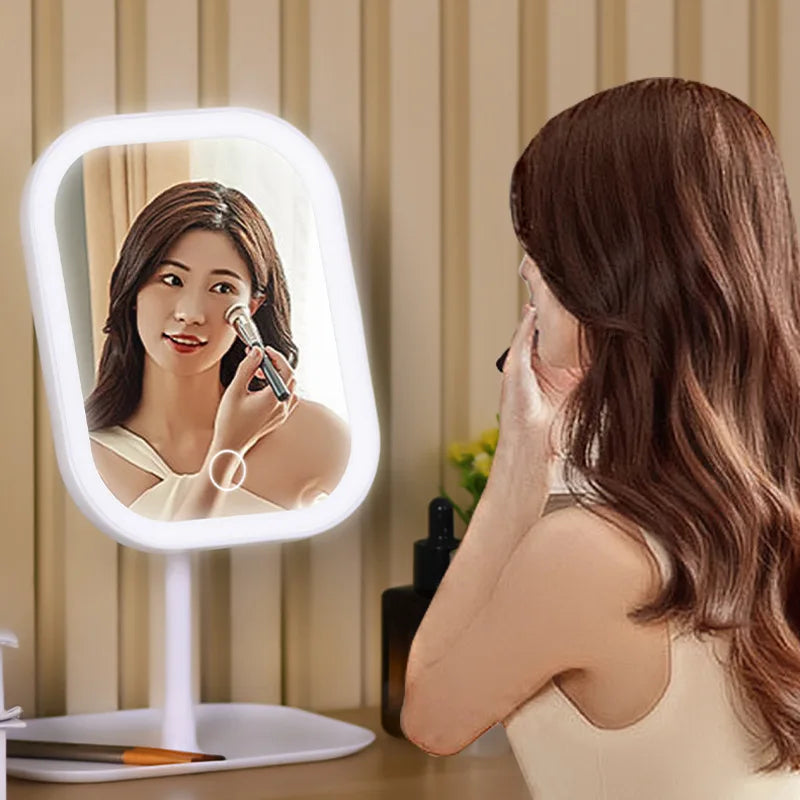 A woman uses an LED touch-sensitive vanity mirror with a ring light to apply makeup.