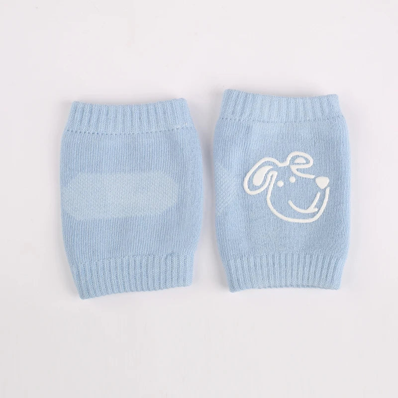 Light blue knitted knee pads for crawling infants with a white dog face design