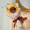 A bouquet of handmade crochet flowers featuring a yellow flower with a brown center, wrapped in white paper and tied with a b