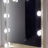 A rectangular vanity mirror with decorative string lights illuminating the frame and reflection.