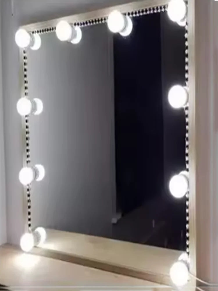 A rectangular vanity mirror with decorative string lights illuminating the frame and reflection.