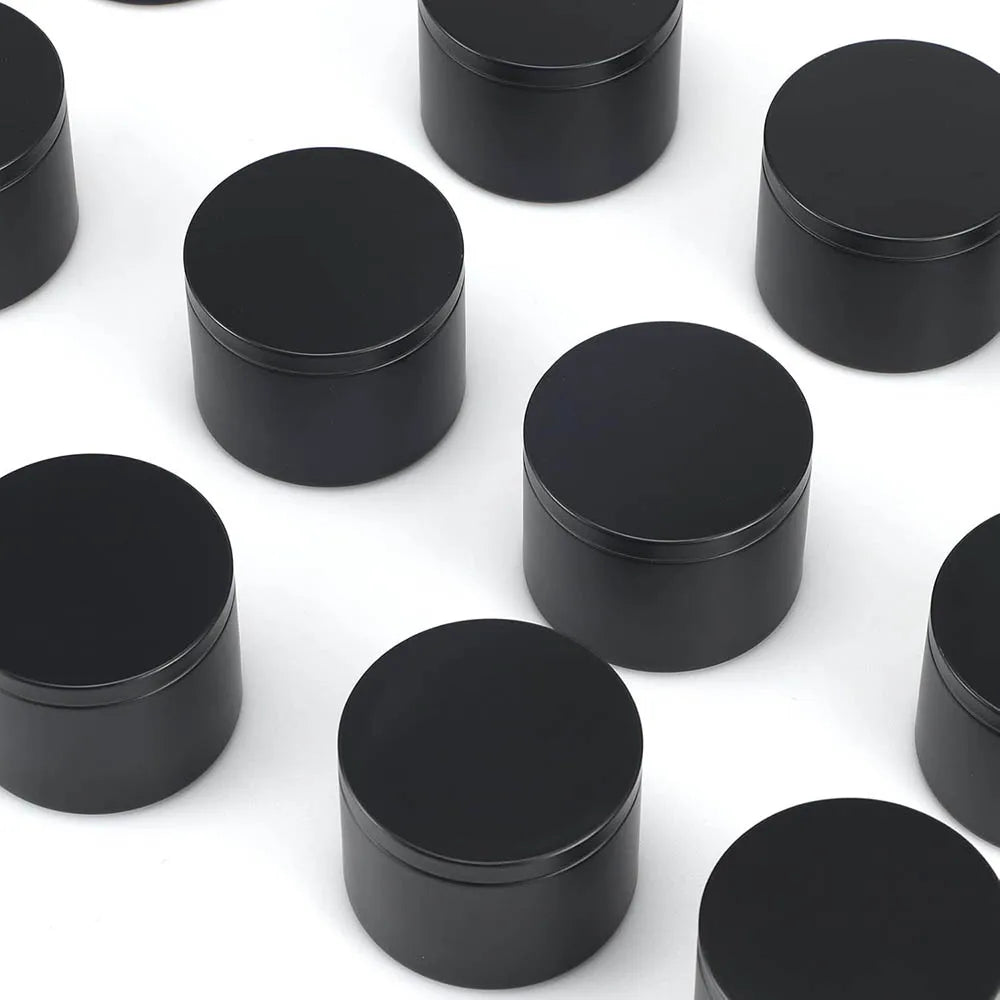 A collection of black candle tin containers with lids arranged on a white surface.