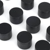 A collection of black candle tin containers with lids arranged on a white surface.