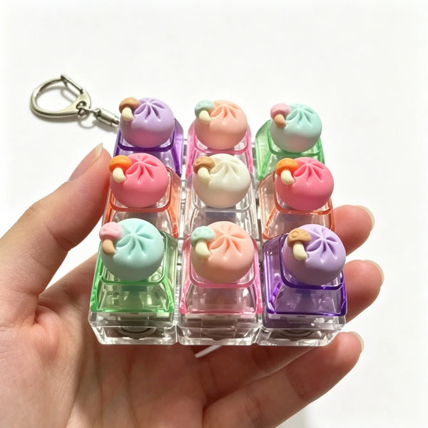 Une main tient un porte-clés clavier de pâte à modeler tactile avec divers dumplings colorés pastel.