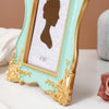 A gold-framed photo frame with a light mint green border and a dark silhouette of a woman on a white background.