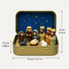 A small nativity scene featuring figures of Mary Joseph and baby Jesus set in a gold-colored metal box with a blue starry bac