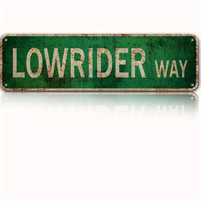 A vintage green metal tin sign with the text LOWRIDER WAY.