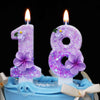 Two purple glitter flower number candles, 1 and 8, on a blue cake.