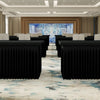 A long hall with rows of black tables draped in elastic fitted spandex tablecloths, leading toward a brightly lit blue floral