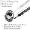 A black acrylic paint pen with a fine tip is shown next to a round, dark gray stone decorated with white dots and a Yin-Yang 