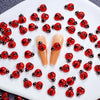 A collection of 50 red and black ladybug resin nail art charms arranged on a white surface.