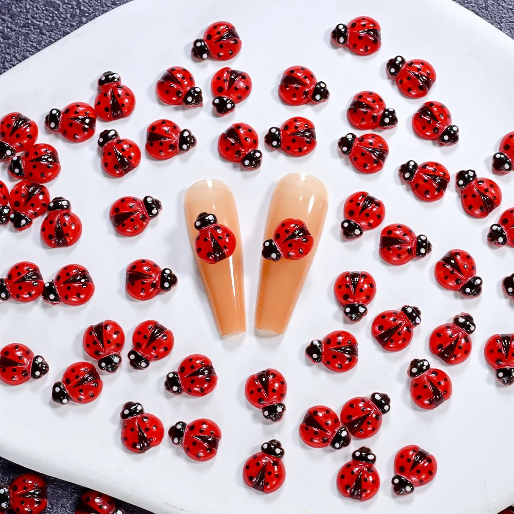 A collection of 50 red and black ladybug resin nail art charms arranged on a white surface.
