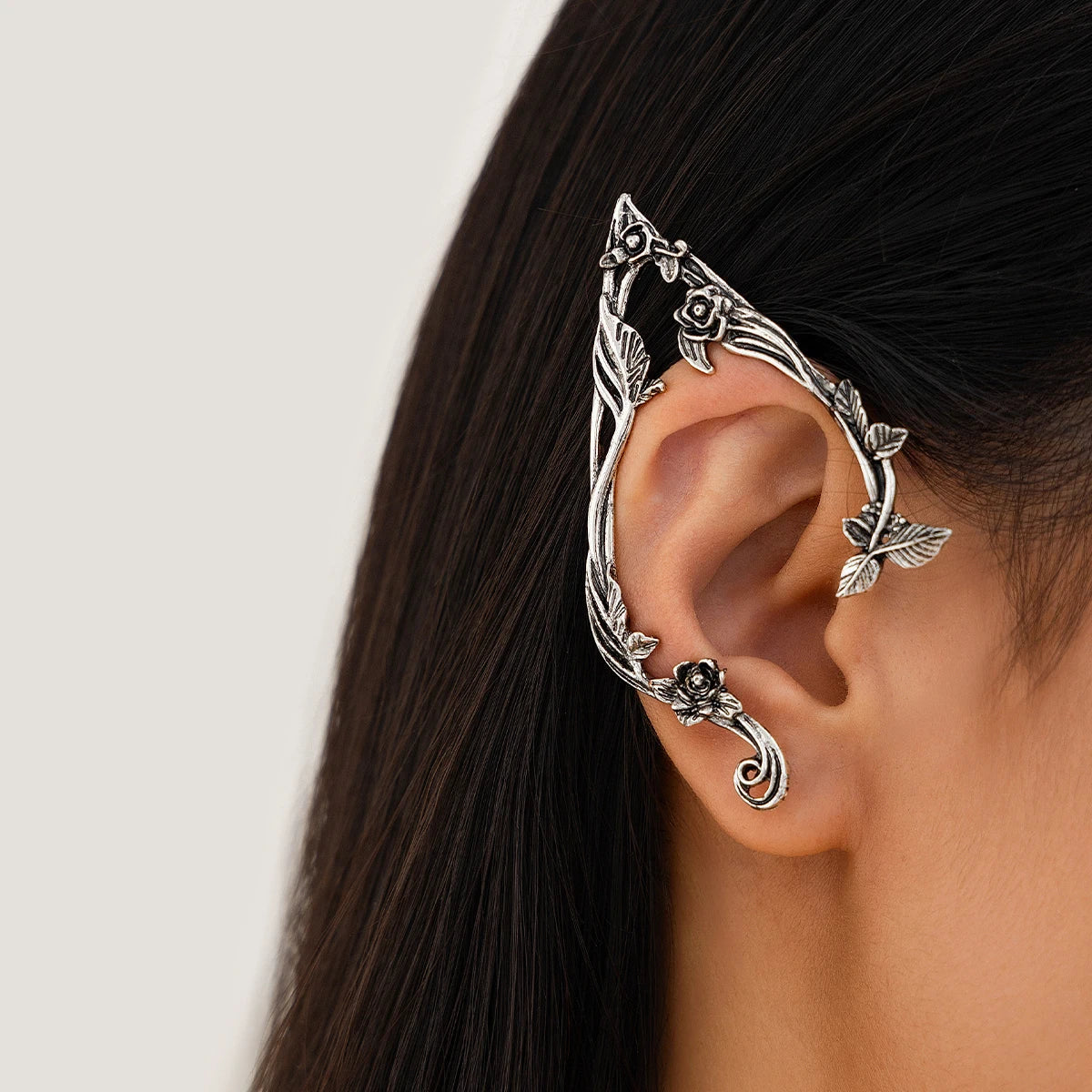 Silver elf flower leaf clip earrings worn on a woman's ear.