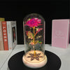 A rose crystal flower in an illuminated glass dome resting on a wooden base.