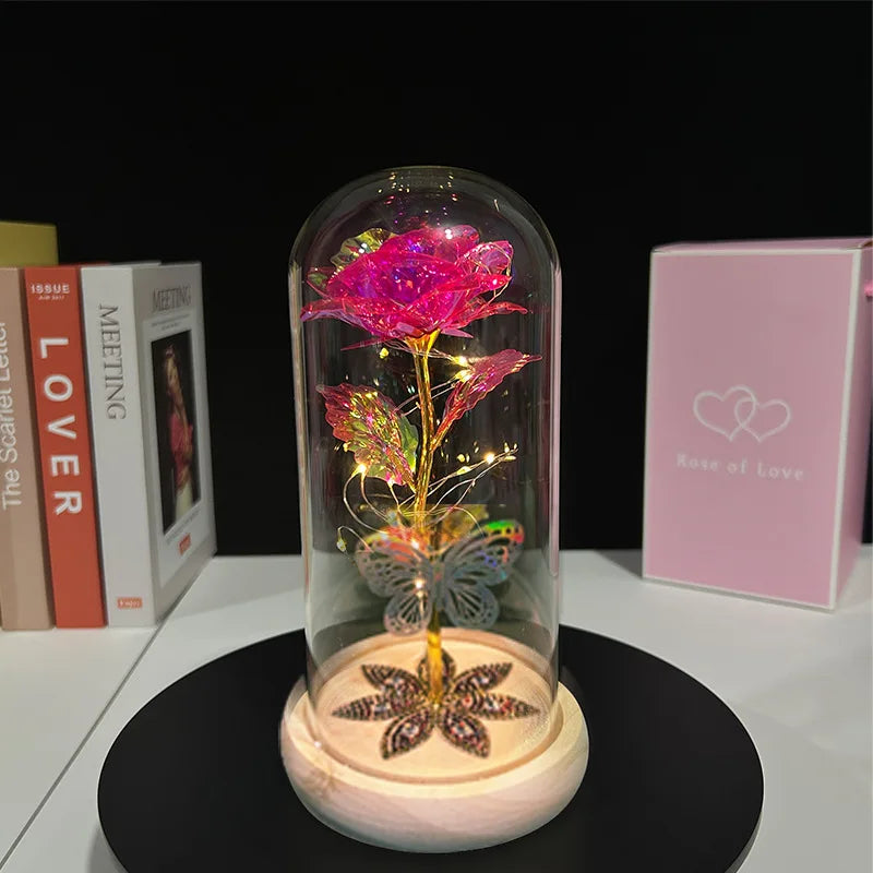A rose crystal flower in an illuminated glass dome resting on a wooden base.