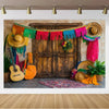 A rustic wooden door decorated with colorful fringed banners and straw hats, set against a textured wall.