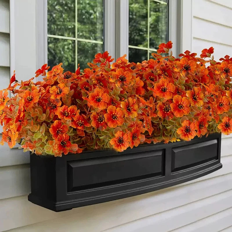 Arrangement de fleurs artificielles d'automne et d'Halloween en pot, sur un mur de revêtement blanc extérieur.