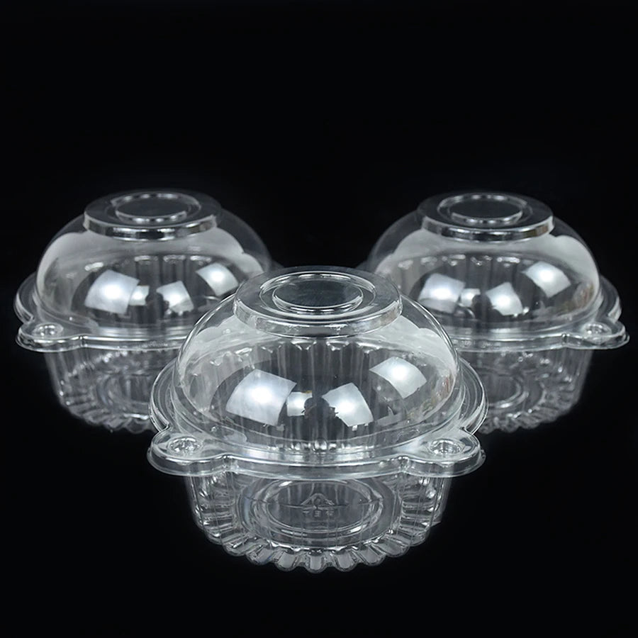 Clear plastic cupcake boxes with decorative rims displayed against a black background.
