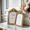 Two ornate gold-framed resin photo frames displayed on a white marble surface.