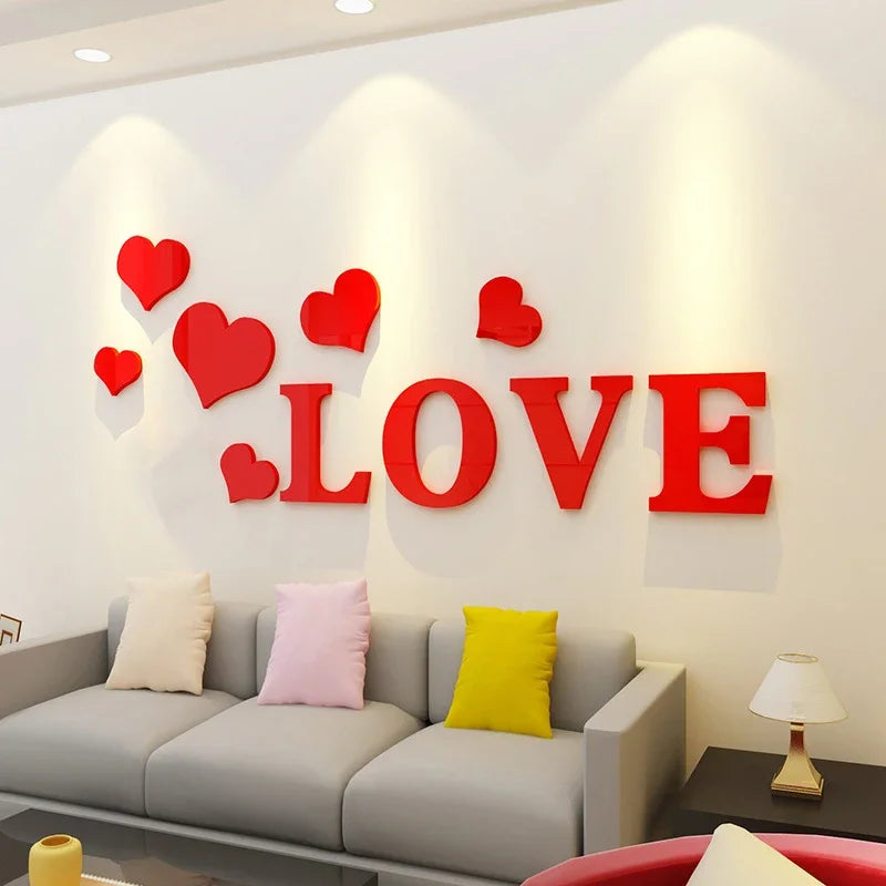 Red acrylic heart wall stickers spelling the word LOVE displayed on a white wall above a gray sofa.