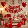 A red heart balloon banner spelling out Happy Birthday decorated with red balloons and gifts on a sofa.