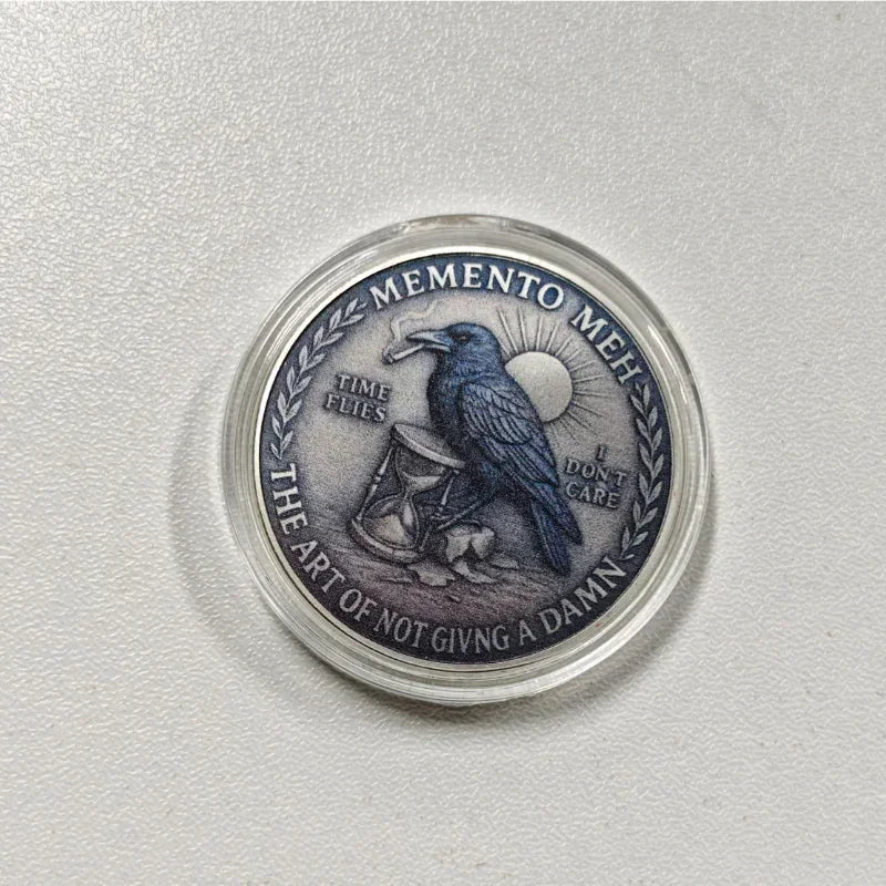 A challenge coin featuring a gothic crow, skull, and text that reads Memento Meh I Don't Care.